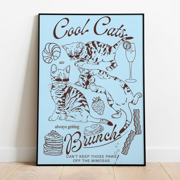 a poster leaning against a wall featuring three kittens alongside breakfast and brunch foods with the phrase cool cats are always getting brunch and the phrase can't keep those paws off the mimosas below
