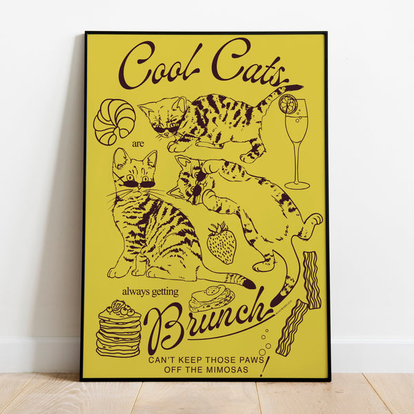 a poster leaning against a wall featuring three kittens alongside breakfast and brunch foods with the phrase cool cats are always getting brunch and the phrase can't keep those paws off the mimosas below