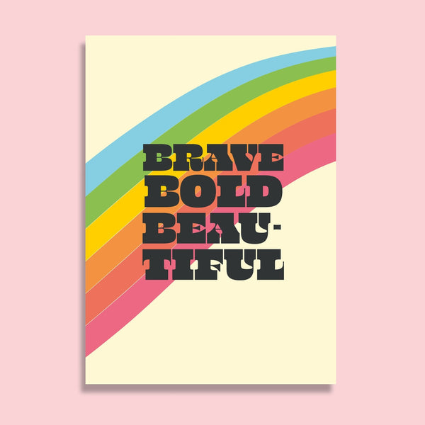 postcard featuring the words brave bold beautiful with a rainbow stripe behind them. the background is cream.
