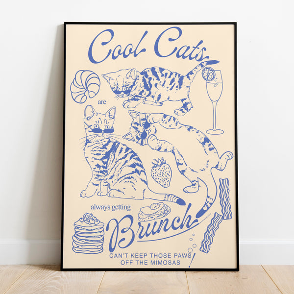 a poster leaning against a wall featuring three kittens alongside breakfast and brunch foods with the phrase cool cats are always getting brunch and the phrase can't keep those paws off the mimosas below