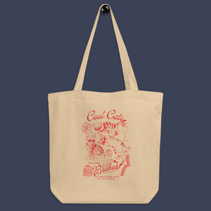 a picture of a tote bag hung on a simple black peg. The tote bag is a natural oyster colour with a red line art design of kittens and brunch food with the phrase cool cats are always getting brunch on it. 