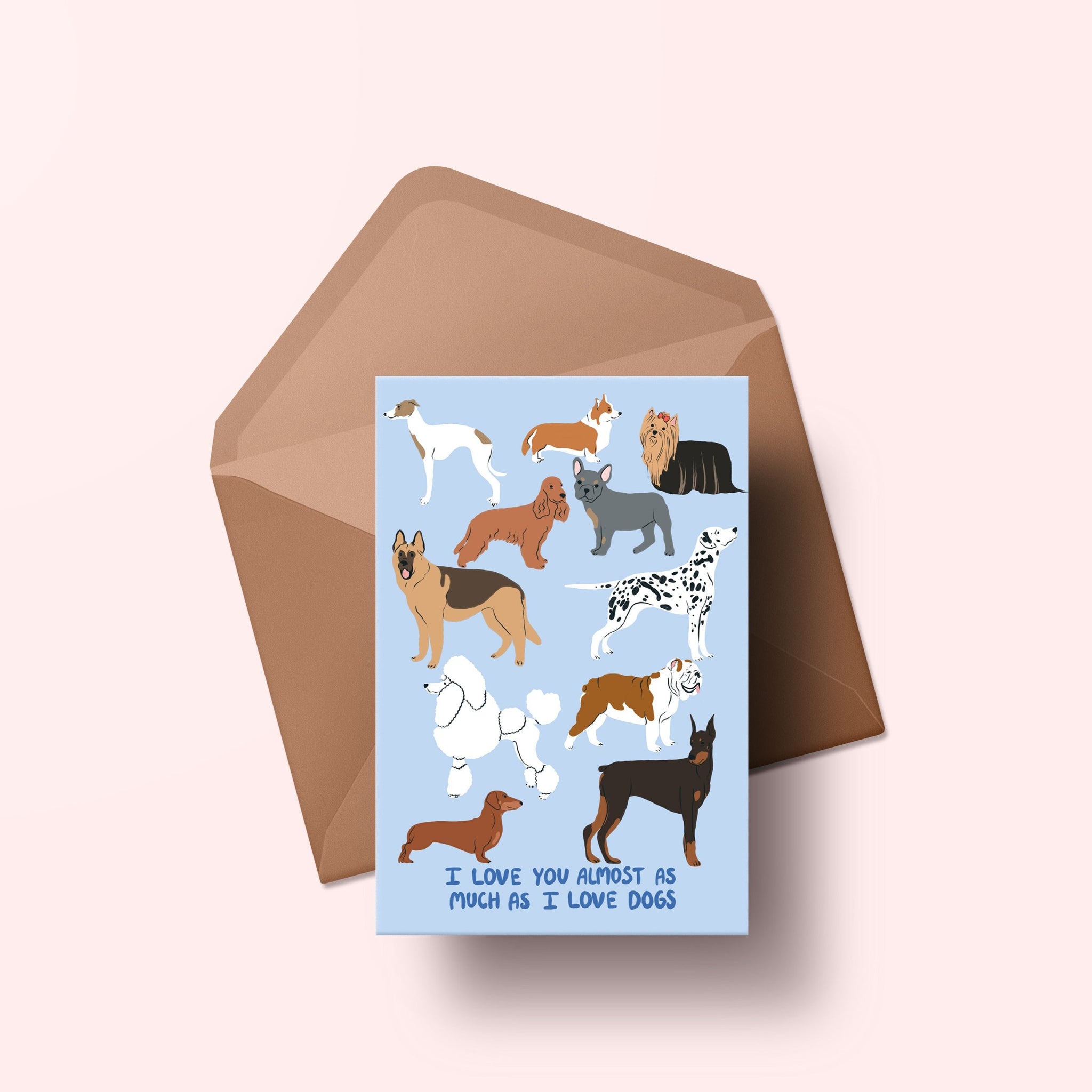 image of a greetings card featuring an illustration of lots of dogs with handwritten text 'I love you almost as much as I love dogs'  The background of the card is a light blue and on top of a recycled kraft material.
