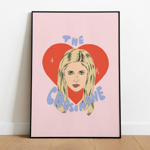 A framed art print of Buffy the vampire slayer illustrated in front of a red heart with the words the chosen one written around her in blue.