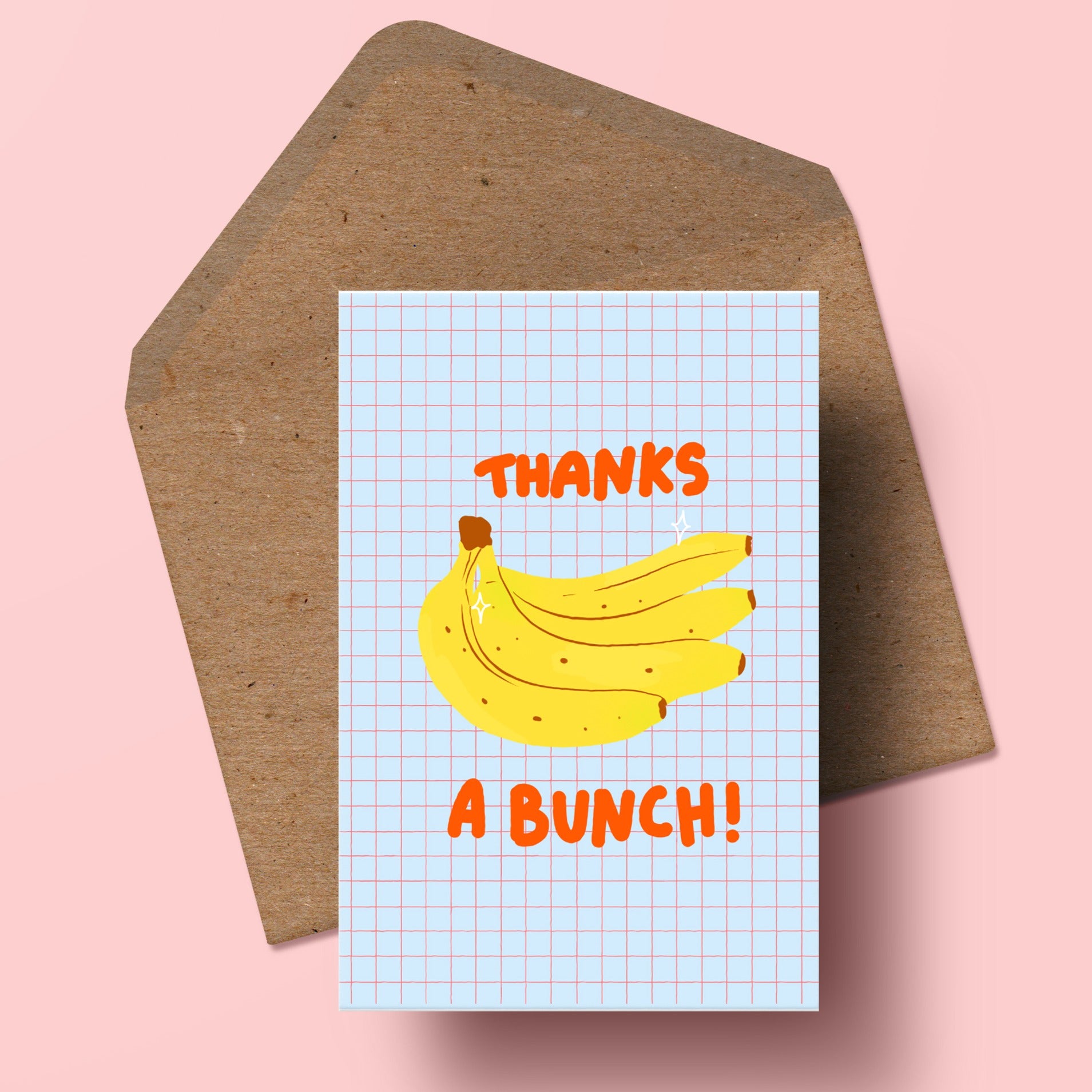 image of a greetings card featuring an illustration of a bunch of bananas with the word thanks above it and a bunch below it. the background of the card is a pale blue with a red check pattern. beneath the card is a recycled kraft envelope.