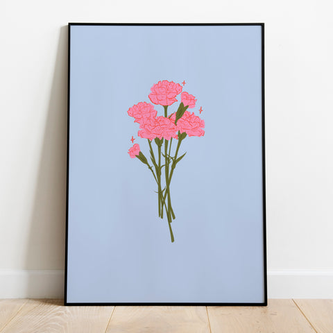 a framed art print of a bunch of pink carnations on a pale blue  background. The frame is leaning up against a white wall and wooden flooring