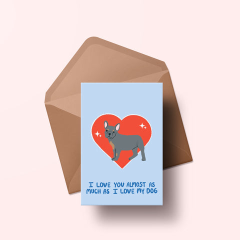 image of a greetings card featuring an illustration of a frenchie with a red heart behind it. The background of the card is a light blue and beneath the heart and dog are the words I love you almost as much as my dog in handwritten lettering in a darker blue shade. Behind the card is an envelope made of a recycled kraft material.