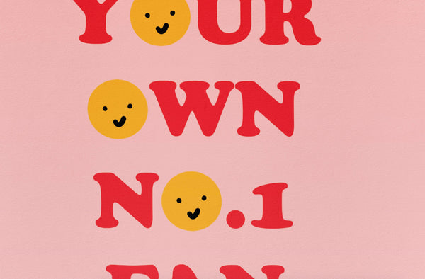 a zoomed in look at a typography print featuring the words 'be your own no.1 fan' the os are replaced with yellow smiley faces. The text is in a 70s style font in red. the background is a mid pink