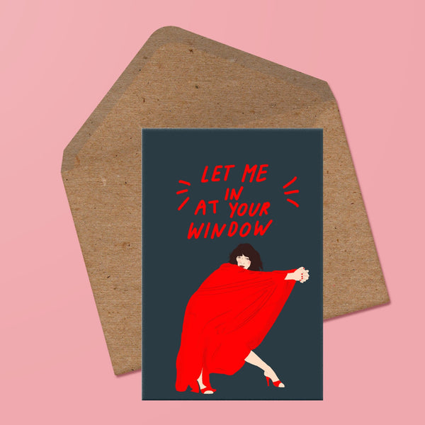 image of a greetings card featuring kate bush in an interpretative dance move pose wearing a red dress. above her are the words 'let me in at your window' in red handwritten text. the background of the card is a deep navy. behind the card is a recycled kraft envelope.