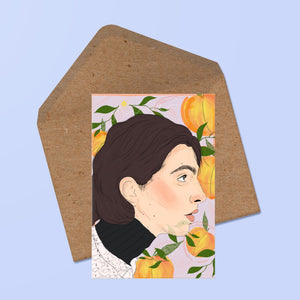 image of  greetings card featuring a portrait of timothee chalamet in profile with a peach motif in the background. behind the card is a recycled kraft envelope.